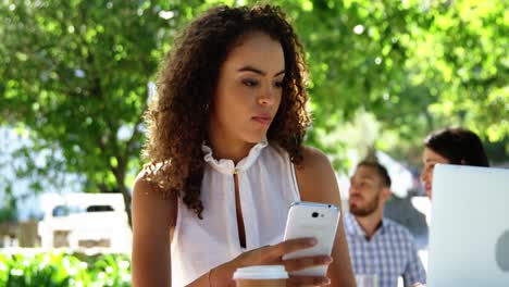 mujer usando computadora portátil y teléfono móvil en un restaurante
