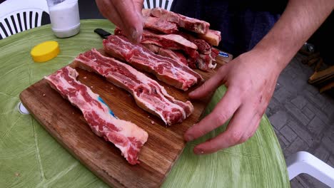 slow motion video of a white man putting salt on the raw meat on a wooden board, before grilling