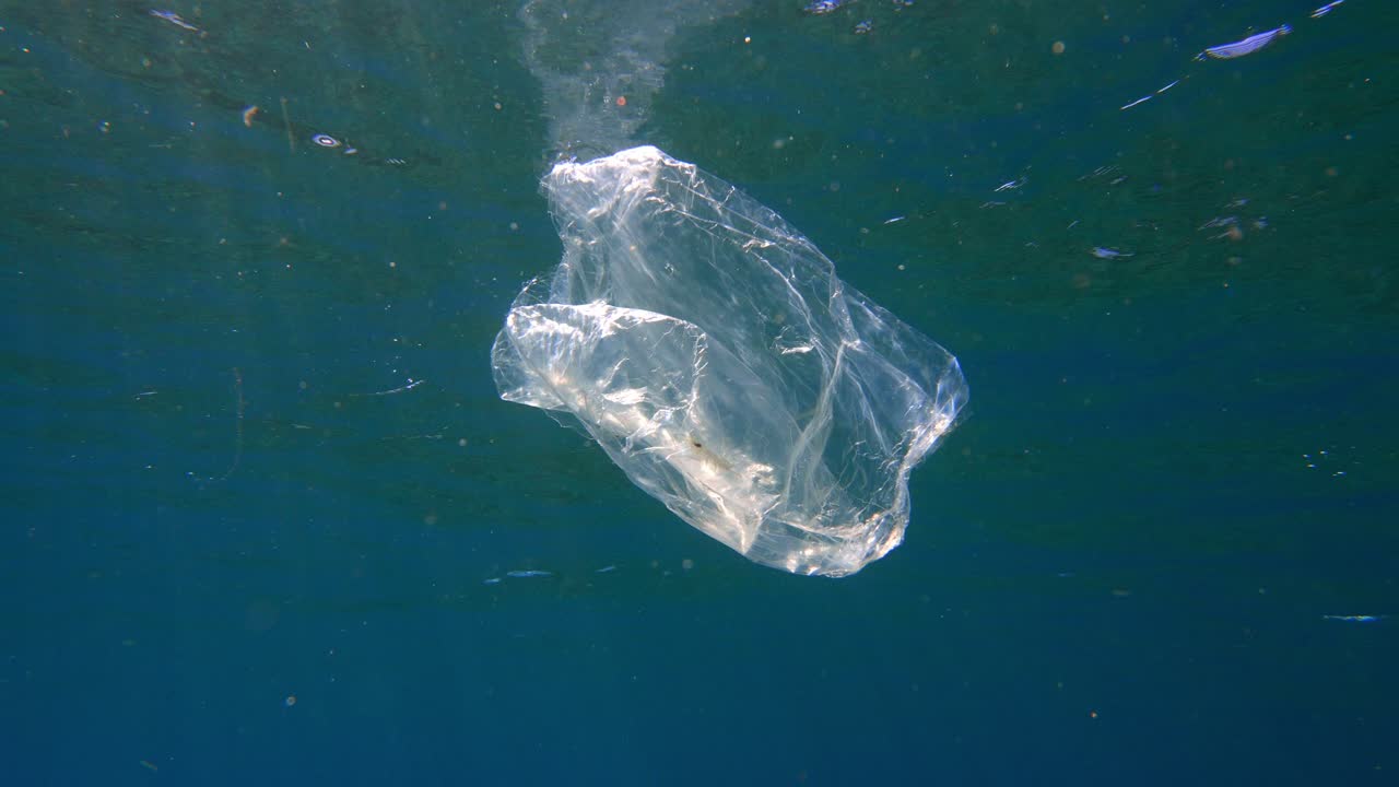 Borsa di plastica trasparente che galleggia in acqua blu vicino alla superficie