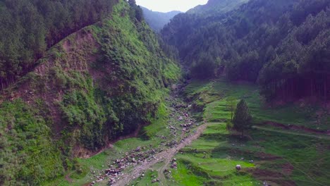 dry river going through mountains, green hills and mountains filled with trees and forest