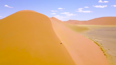 Aerial-over-a-man-hiking-in-the-rugged-desert-landscape-and-sand-dunes-near-Dune-45-in-Namibia-Africa