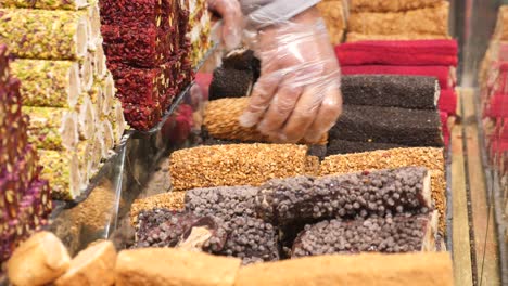 a close up of a hand picking out turkish delight from a display