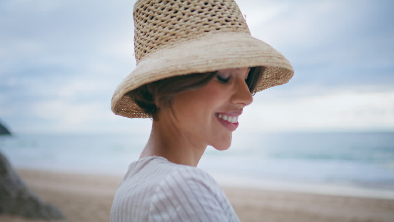 Portret van lachende vrouw die op het strand in de camera kijkt. Aantrekkelijk reismeisje aan de oceaan.