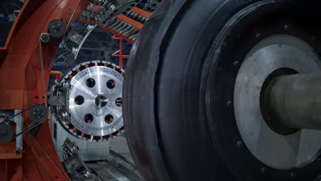 Closeup-tire-factory-mechanism-working-process-with-uniformed-worker-checking