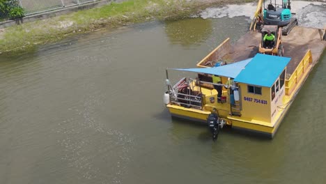 aerial view of a barge with machinery operating in a canal near luxury homes in broadbeach waters, queensland