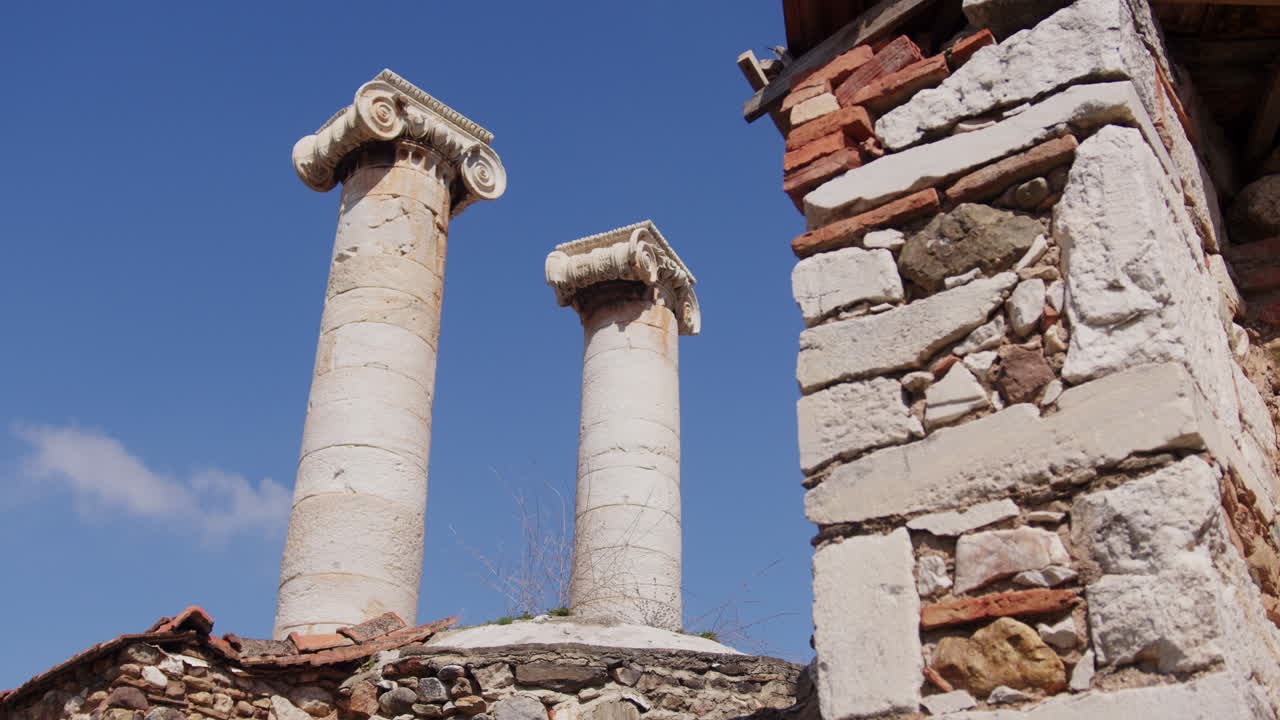 antiguas columnas detrás de una pared de ladrillo en el templo de artemisa en sardis