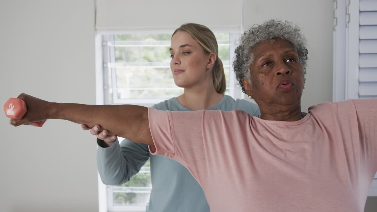 Caucasian female physiotherapist with senior woman exercising, copy space, slow motion