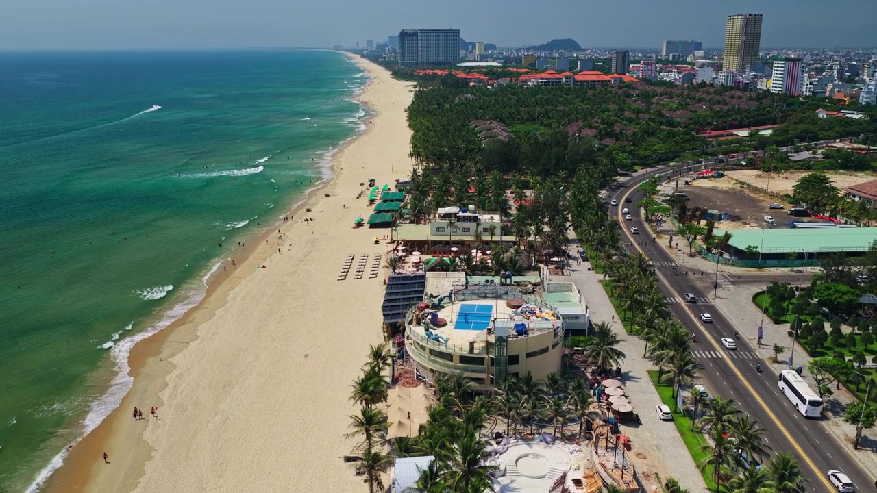 Da Nang Vietnam strandvej luftfoto med drone af luksusresort, kystmotorvejstrafik, bybillede og landskabsudsigt.