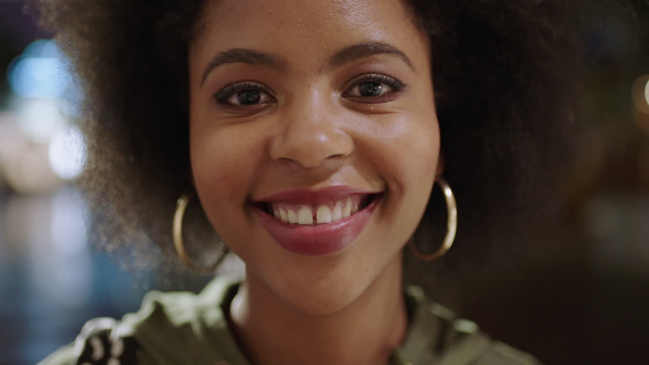retrato en primer plano de una linda mujer afroamericana con afro sonriendo feliz mirando a la cámara sintiéndose confiada