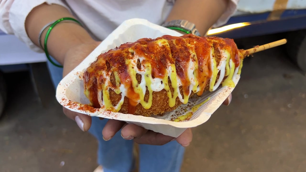 Korean cheese corn dog prepared in Indian style with extra cheese and sauce.