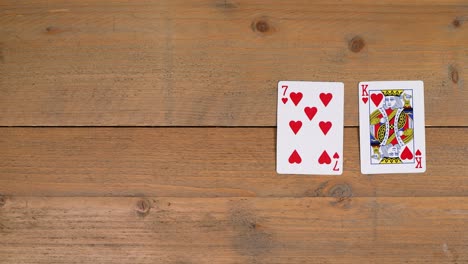 a person laying out a flush with hearts on a wooden table to educate the viewer on how to play poker