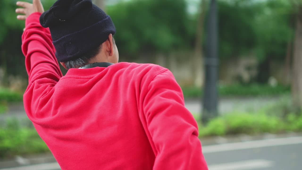 Rear View Of Young Man Standing By The Road And Hailing Taxi