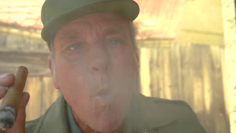 closeup of arrogant and haughty mature male, blowing smoke from cigar directly at the camera