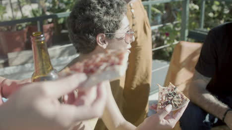 mulher feliz sentada com amigos no telhado e comendo pizza