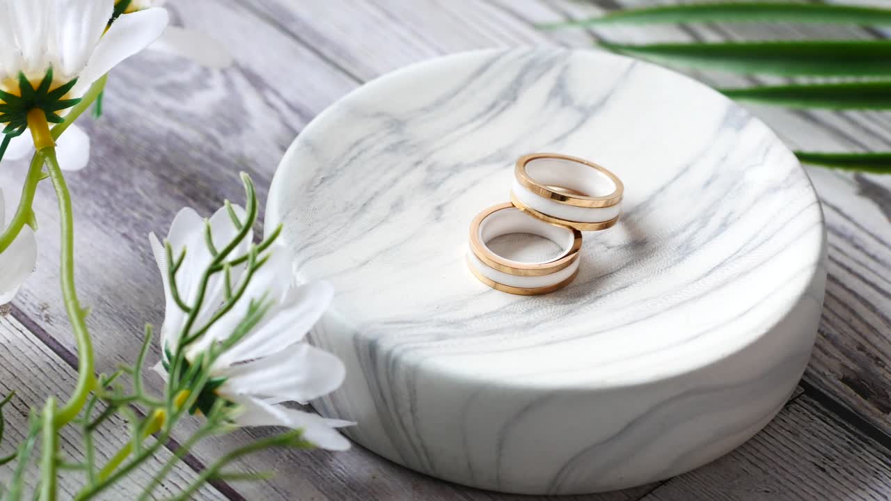 Elegant Gold and White Rings on a Marble Dish with Flowers