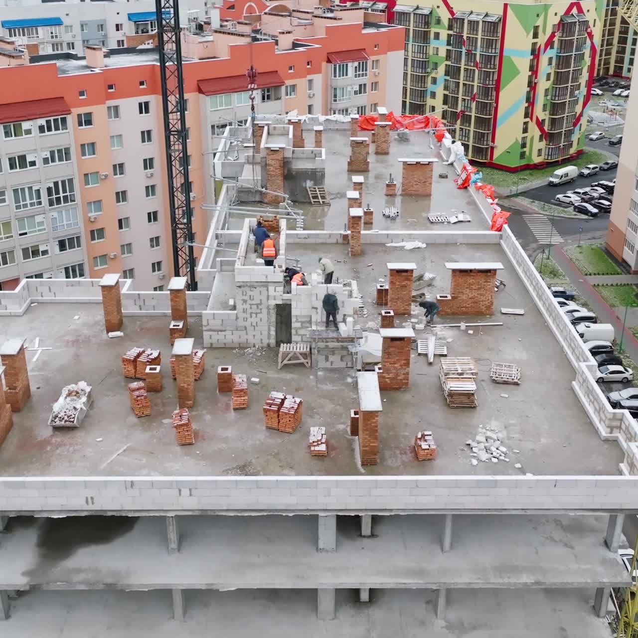 New block of flats being constructed in the area. Slow approach to the construction site on the roof of the building with people working at it