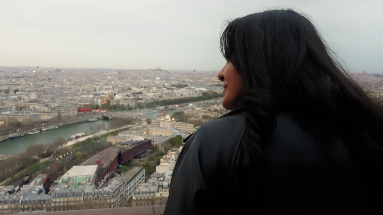mujer de vuelta a la cámara disfrutando de las vistas de la torre eiffel durante el día