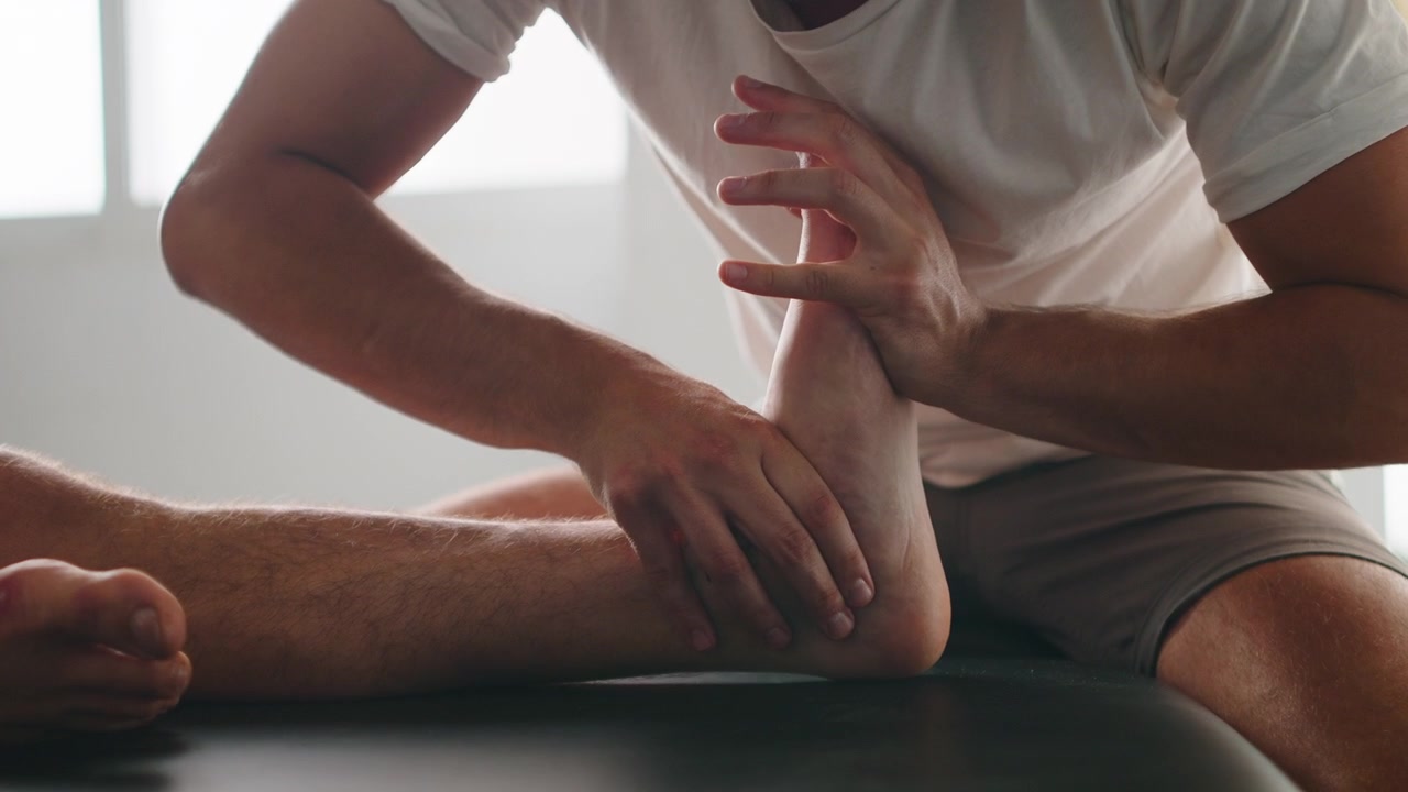 Physiotherapeut führt Knöchelmobilisierung bei Patient durch.