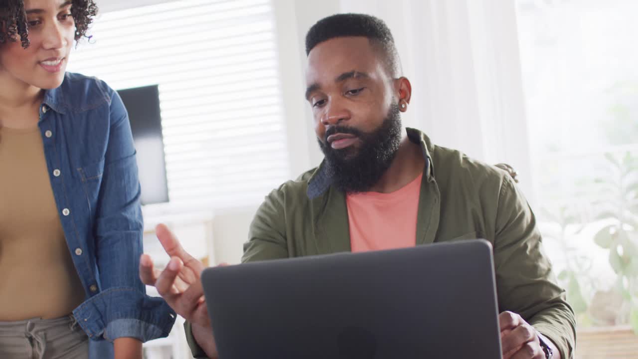 Diverse male and female friends using laptop and talking, working at home in slow motion