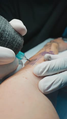 close-up of a tattoo artist applying a music notes tattoo