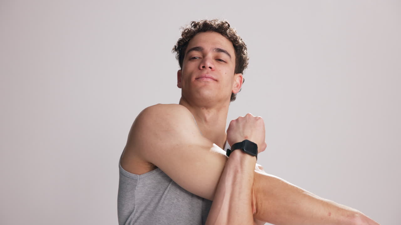 Joven estirando brazos y hombros en el estudio