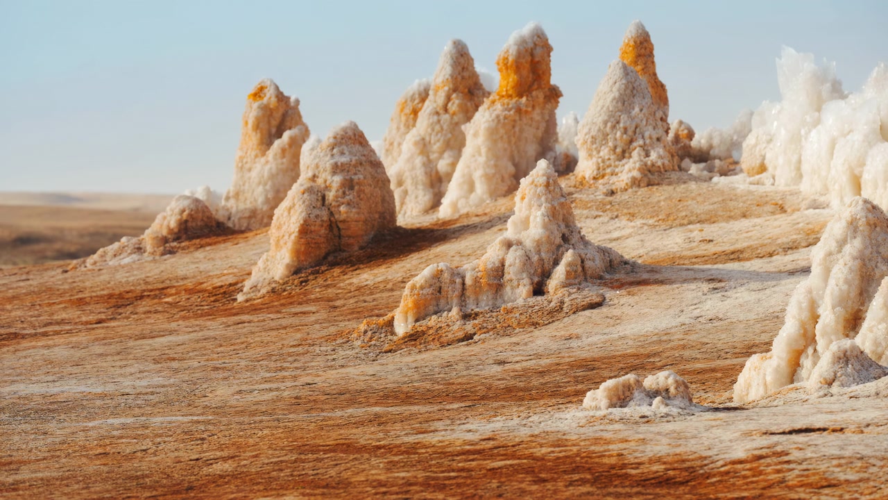 Amplia escena panorámica en movimiento de una llanura incrustada de sal con espiras cristalinas agrupadas en forma de cono y montículo, luz diurna suave, terreno texturizado, horizonte distante y una suave luz brillante sobre la superficie áspera