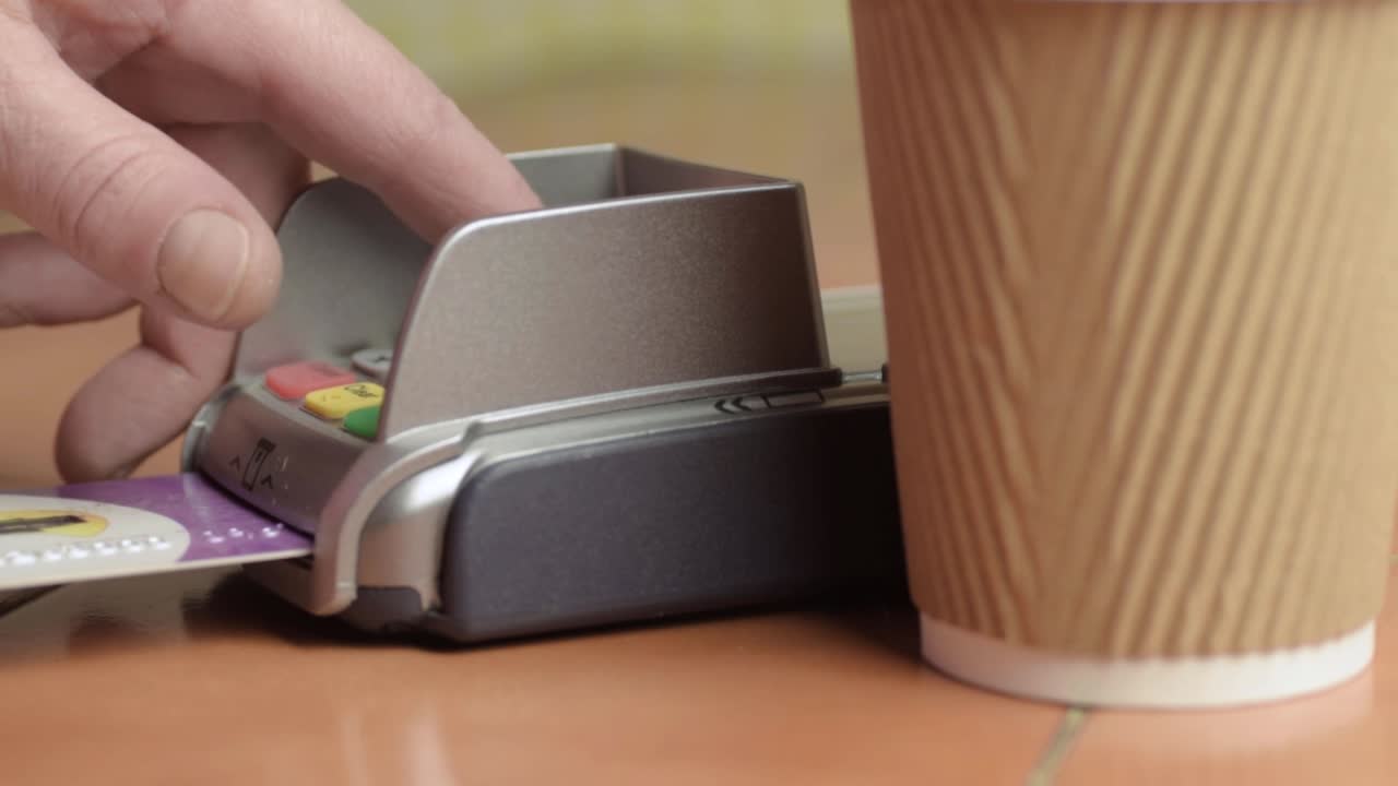 Hand paying by card with take out coffee cup close up shot