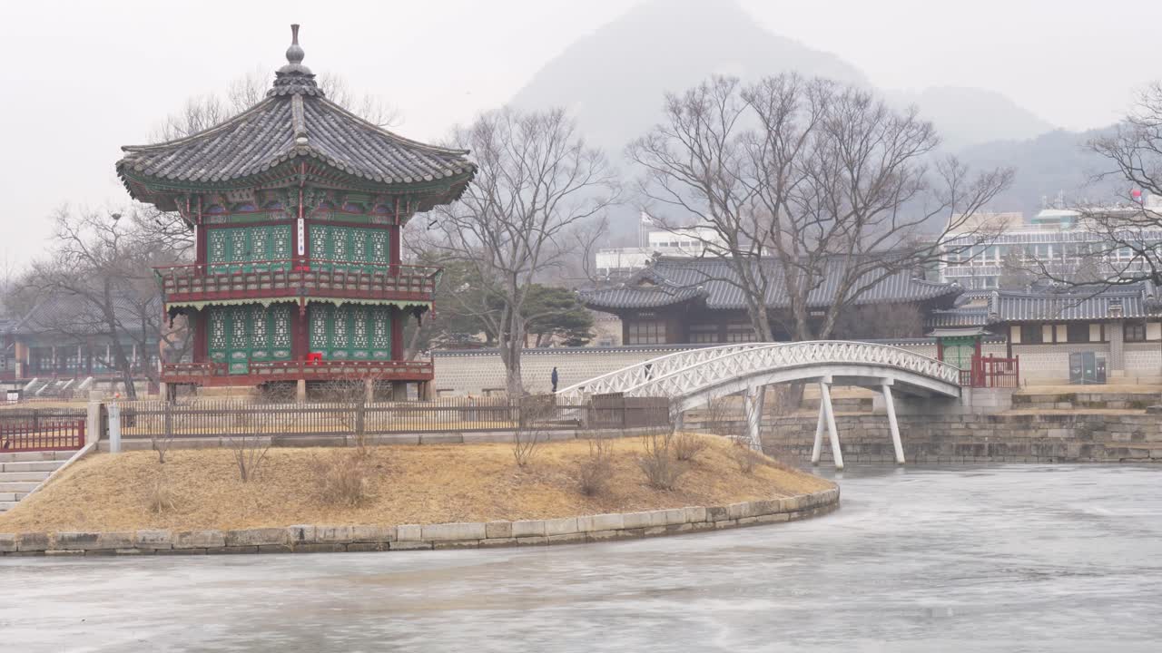 Phong cảnh quay chậm của Đình Hyangwonjeong với cây cầu bắc qua hồ đóng băng gần Khu vườn Bí mật trong khuôn viên Cung điện Gyeongbokgung ở Seoul, Hàn Quốc. Một điểm đến du lịch Châu Á.