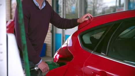 hombre impaciente llenando de combustible un coche en una gasolinera