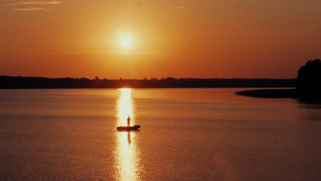 Luftaufnahme-Von-Männern,-Die-Abends-Vor-Strahlender-Sonne-Vom-Boot-Aus-Fischen