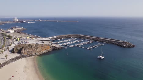 orbiting shot over sailing boats moored on port by emerald beach water, sines