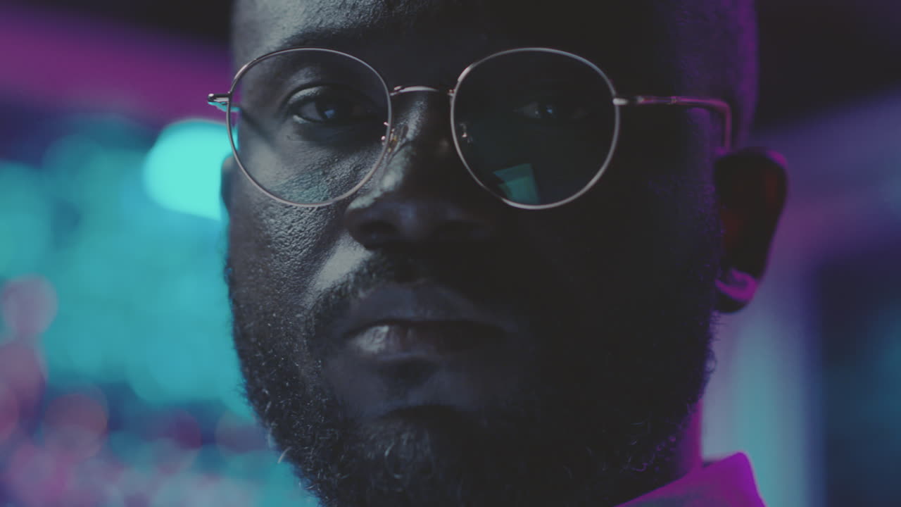 Close-up portrait of a man with glasses in neon light