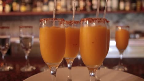 close up shot of few glasses of orange citrus refreshment cocktails drink inside a bar