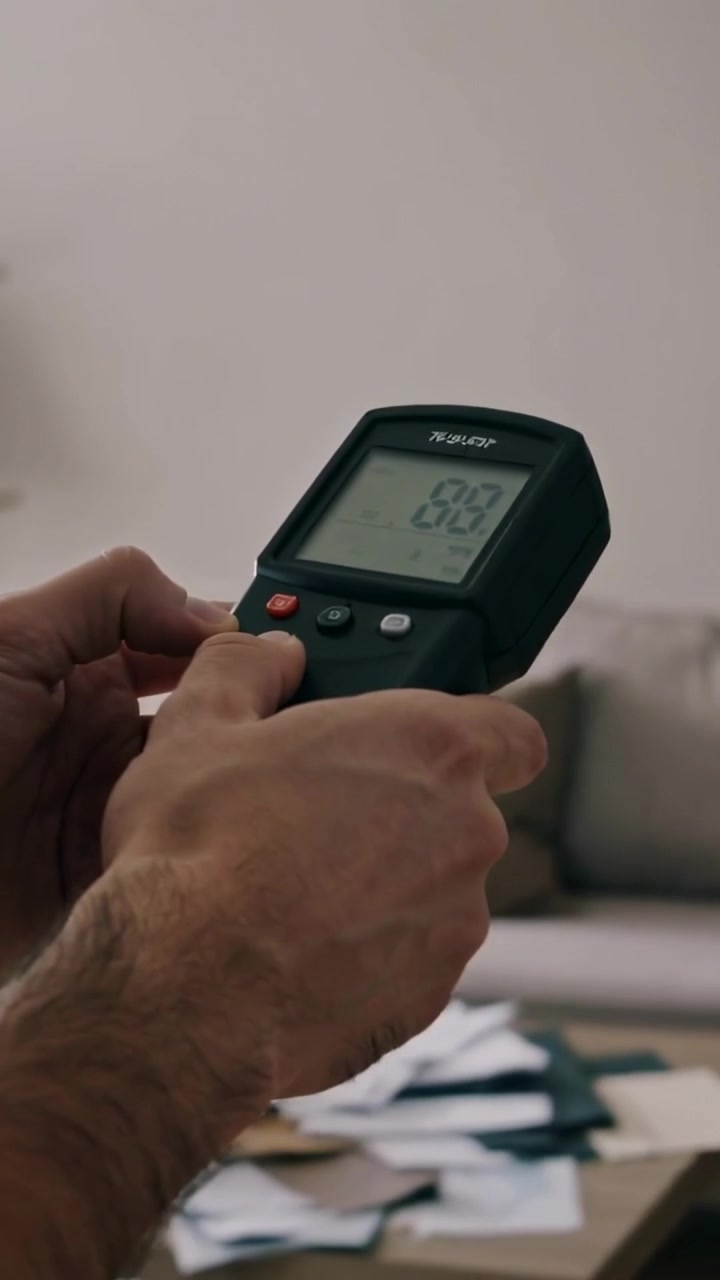 Vertical video: Pressing male hands in short sleeves operating digital meter at home, reading LCD