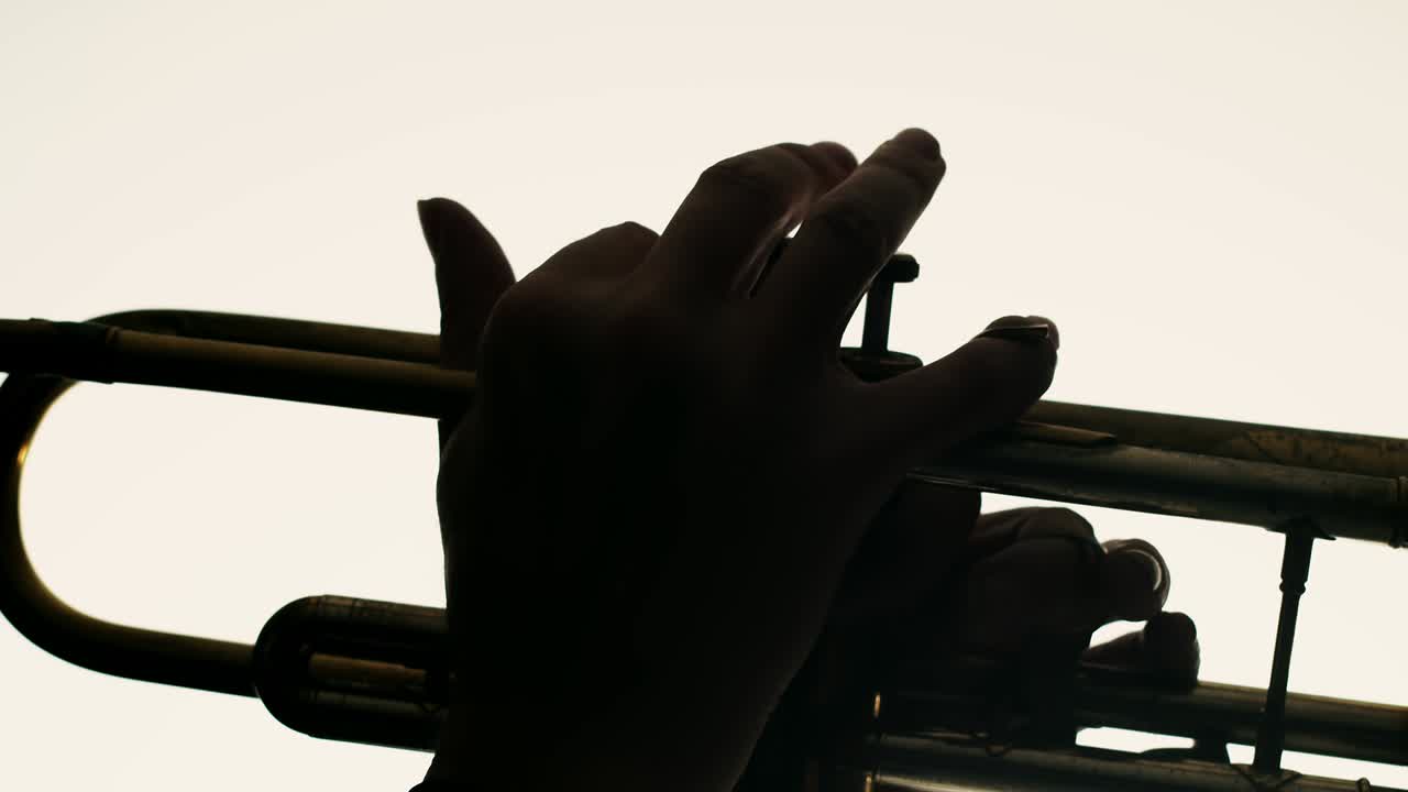 Closeup of male hands playing trumpet on white background. Man plays jazz on trumpet in studio. Musician plays an instrument