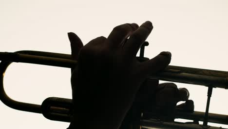 closeup of male hands playing trumpet on white background. man plays jazz on trumpet in studio. musician plays an instrument