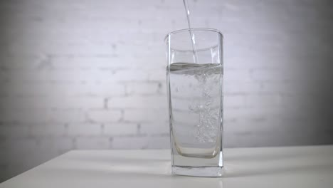 테이블 위에 있는 유리잔에 신선한 미네랄 물을 부어주고, 색 바탕에 산소 공이 있는 신선한 스파클링 음료