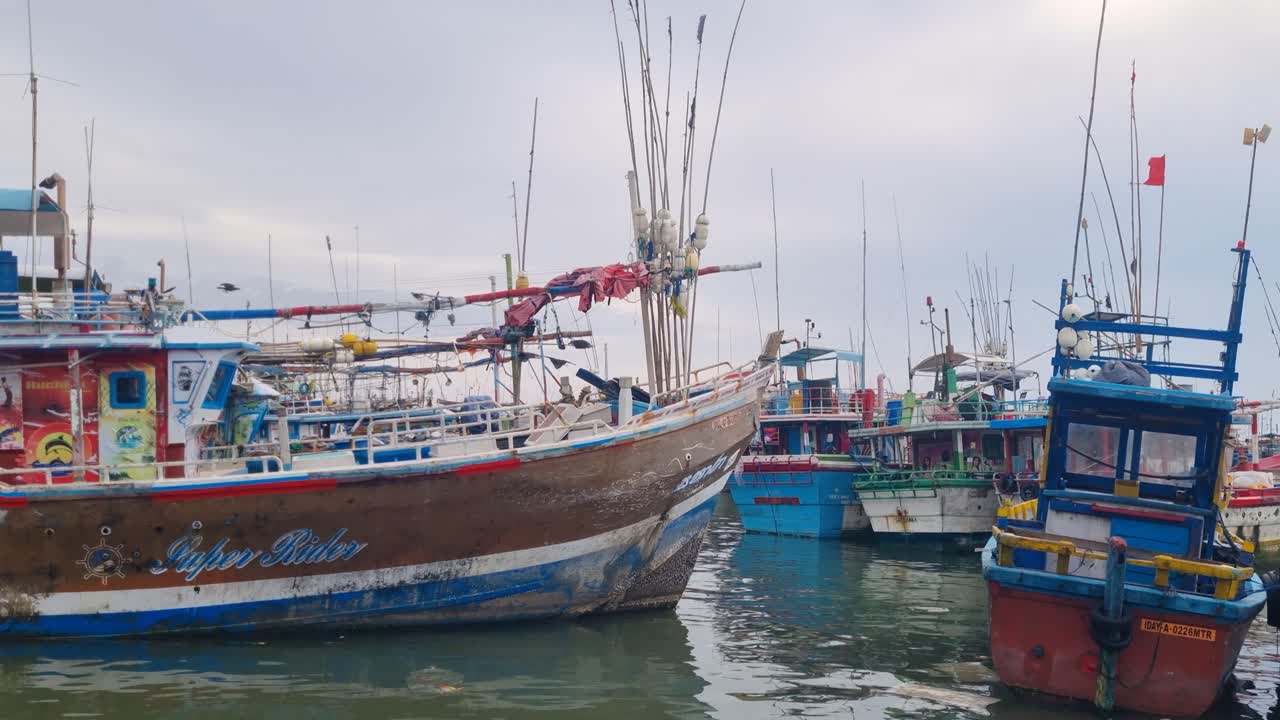 At Dondra Port Fishing Market, southern Sri Lanka, colorful traditional fishing boats rest side by side under an overcast monsoon sky, reflecting vibrant coastal life