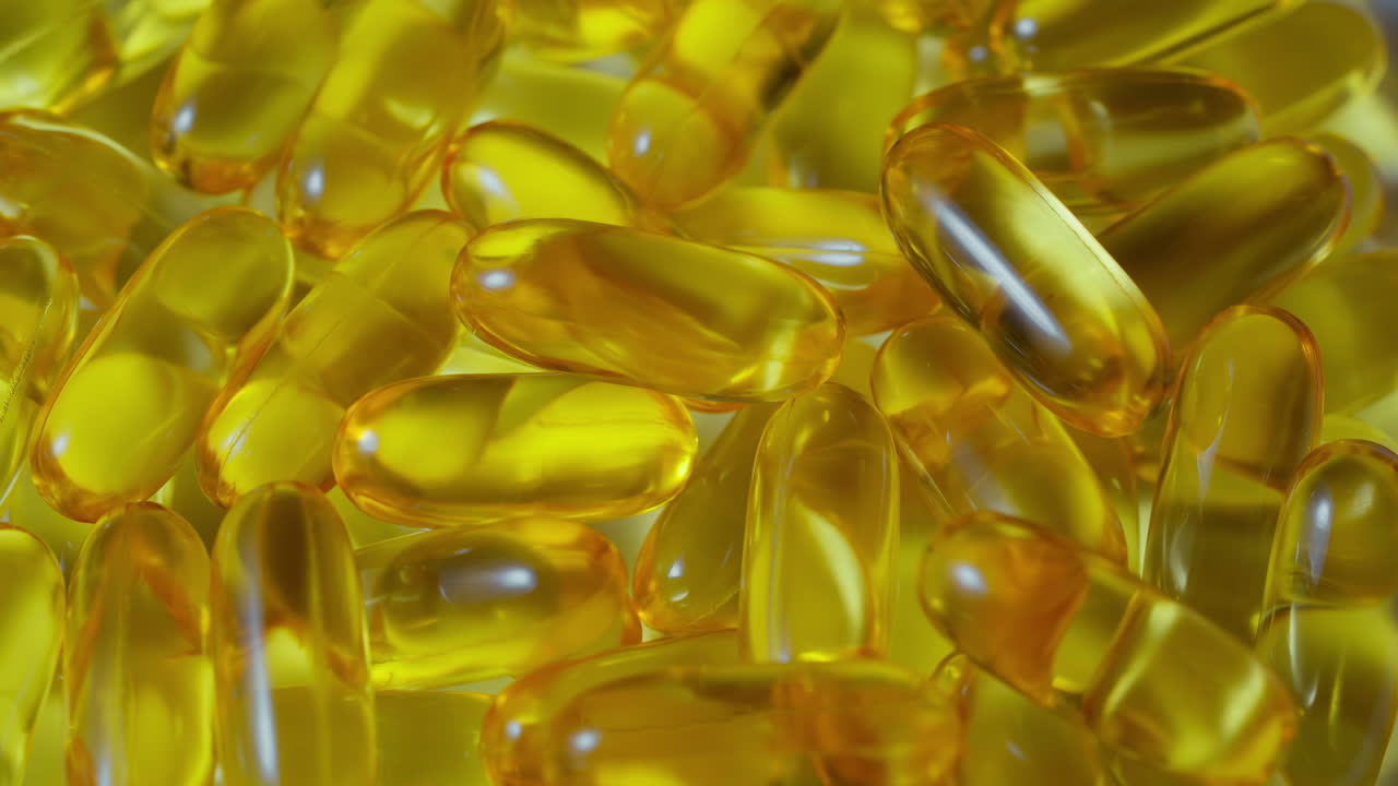 las píldoras de aceite de pescado omega 3 de primer plano caen sobre el fondo blanco, la textura de las cápsulas naturales de vitamina e