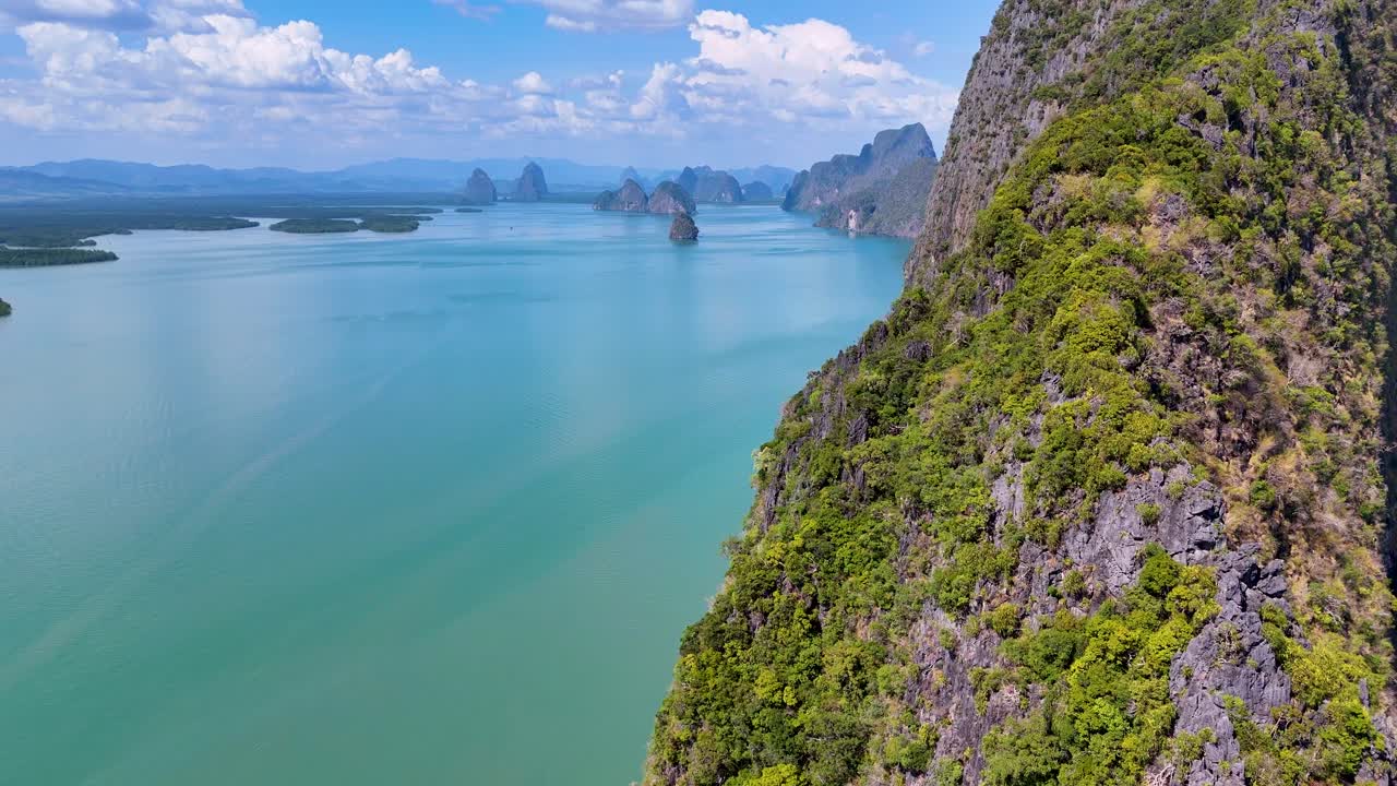 Drone footage captures lush cliffs and turquoise waters in Phang Nga Bay, Thailand, showcasing stunning natural beauty and vibrant colors