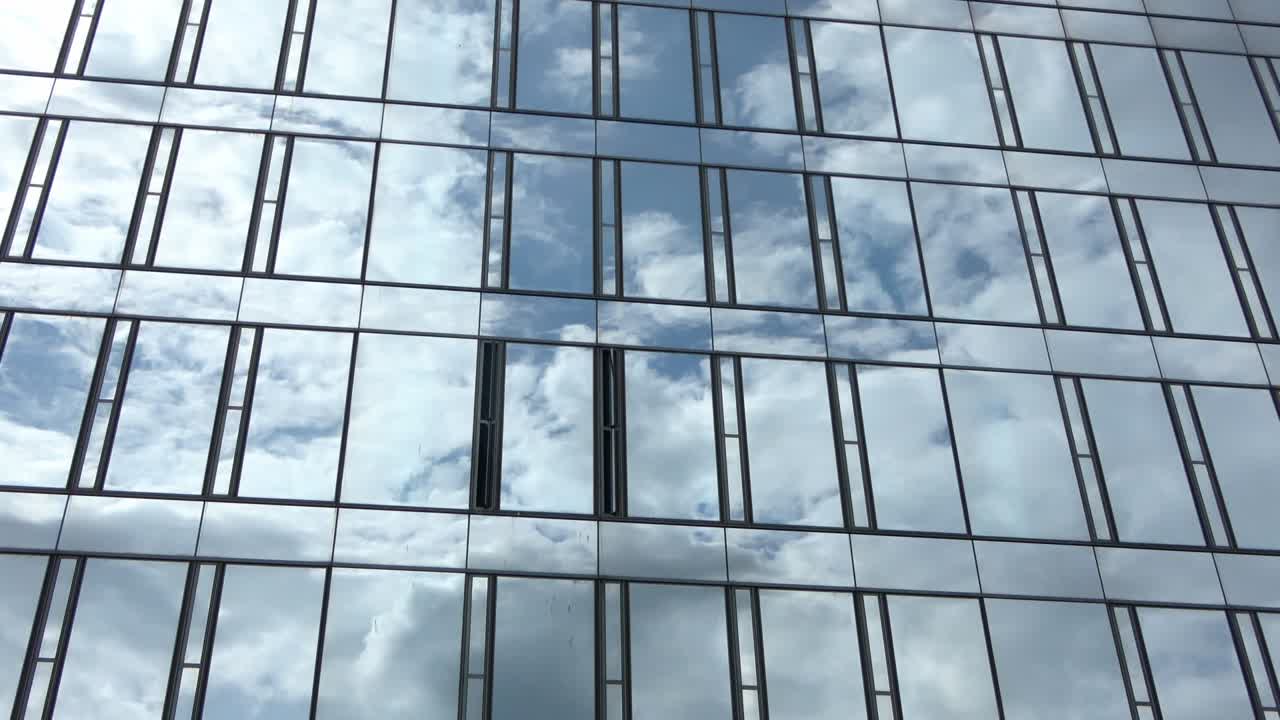 lapso de tiempo de un cielo azul de verano con nubes que se reflejan en la fachada de vidrio de un edificio de oficinas