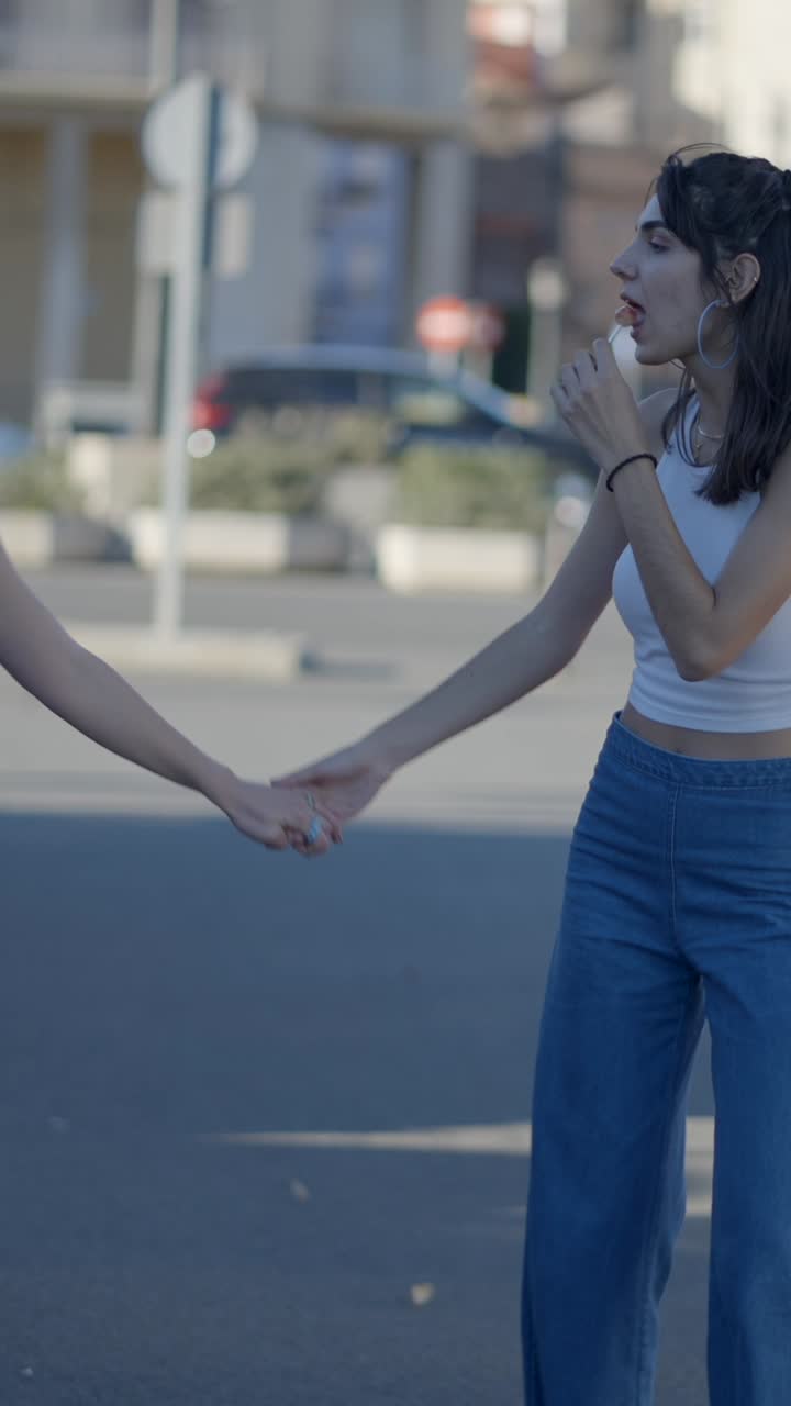 Two Young Women Holding Hands and Walking on an Urban Street