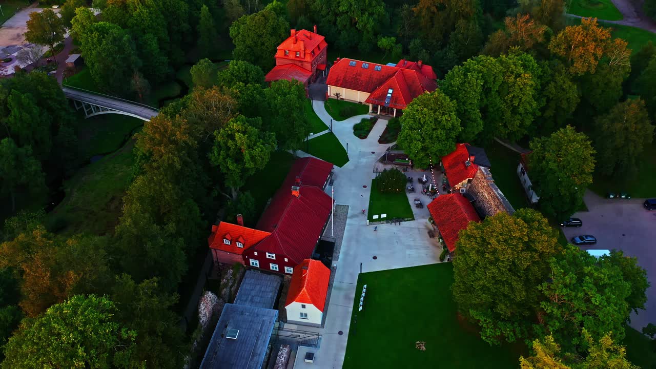 Red-roofed estate buildings surrounded by trees and pathways in elevated view
