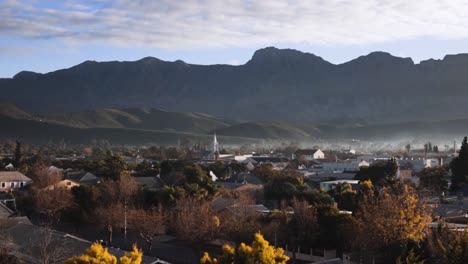 Pan-shot-over-urban-area-in-morning-light-with-misty-mountain-range-in-background