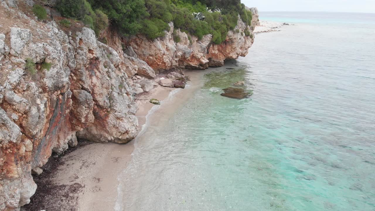 Vista aerea con drone di scogliere rocciose e mare limpido con acqua turchese.