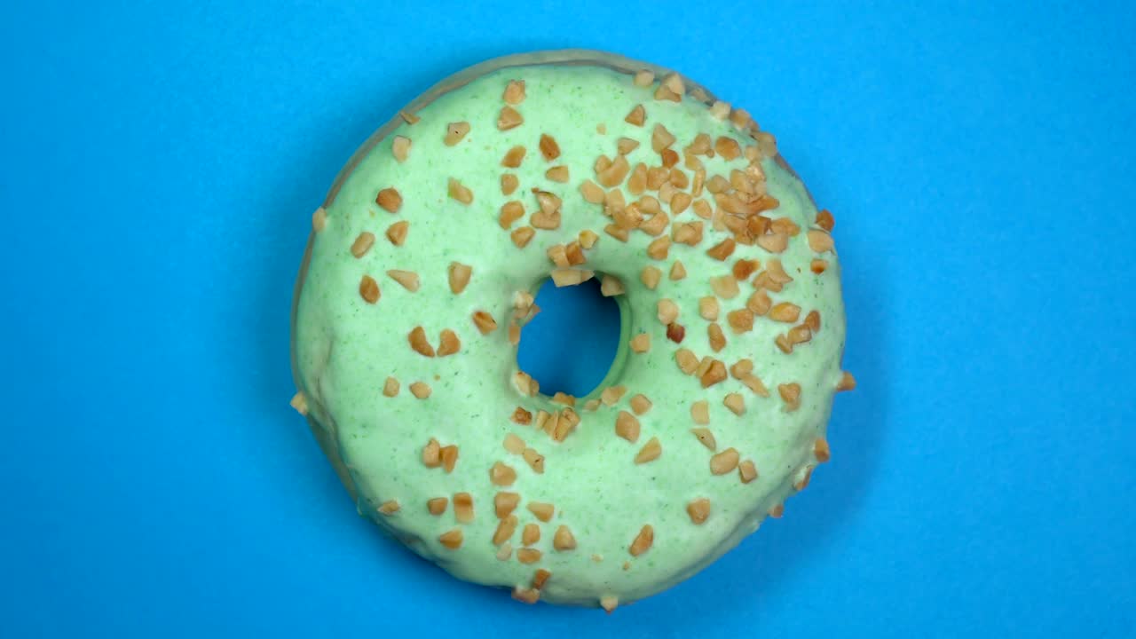 saboroso y fresco rosquilla rosquilla macro disparo de primer plano girando sobre un fondo azul.
