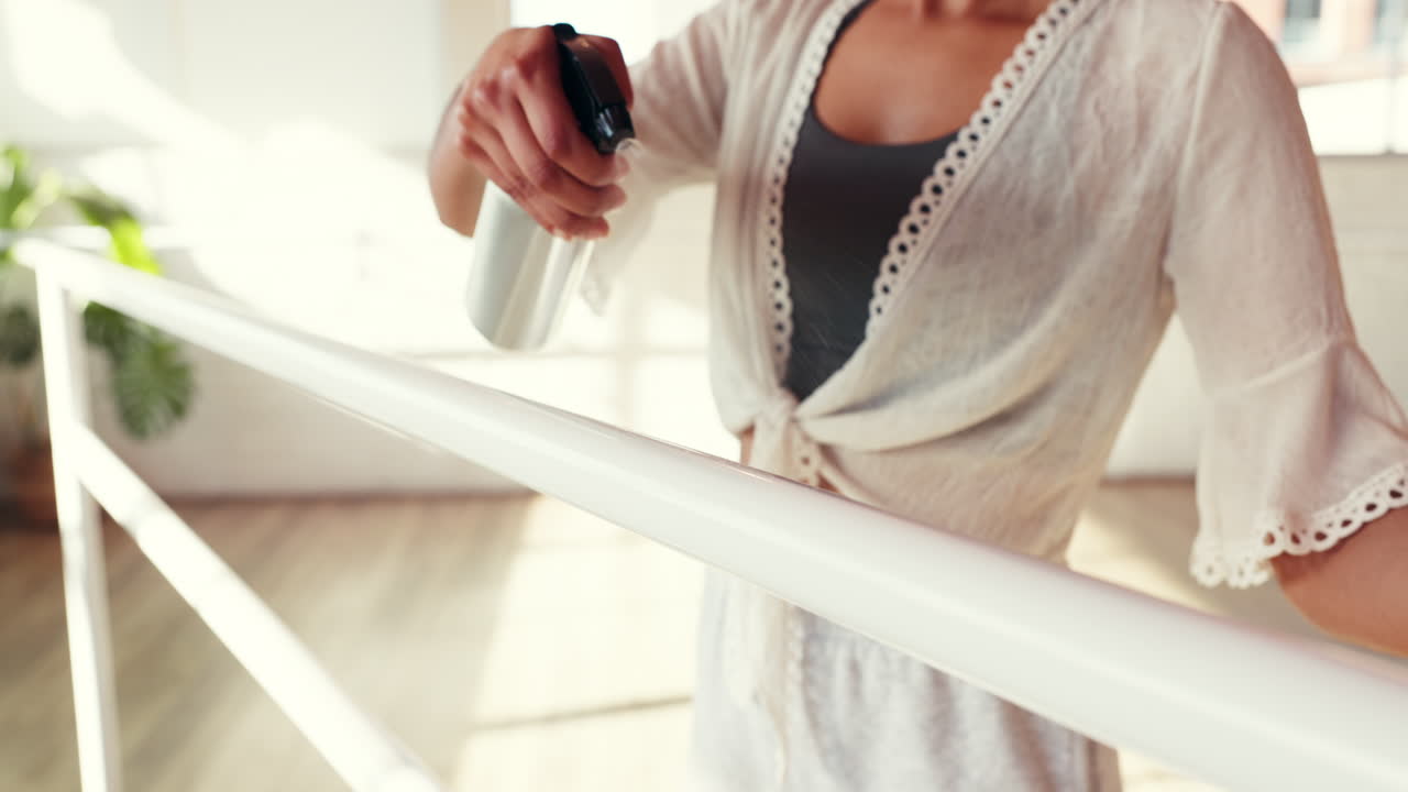 Woman Cleaning Ballet Barre with Spray and Towel