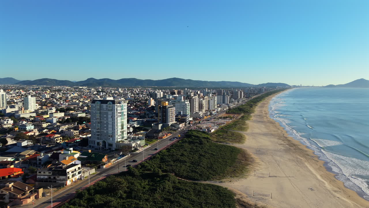 Vista aérea frontal revela Navegantes e sua longa praia de areia em Santa Catarina, Brasil, em uma manhã calma