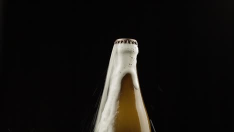 man shakes a bottle of beer. beer begins to pour out with foam rom under the lid