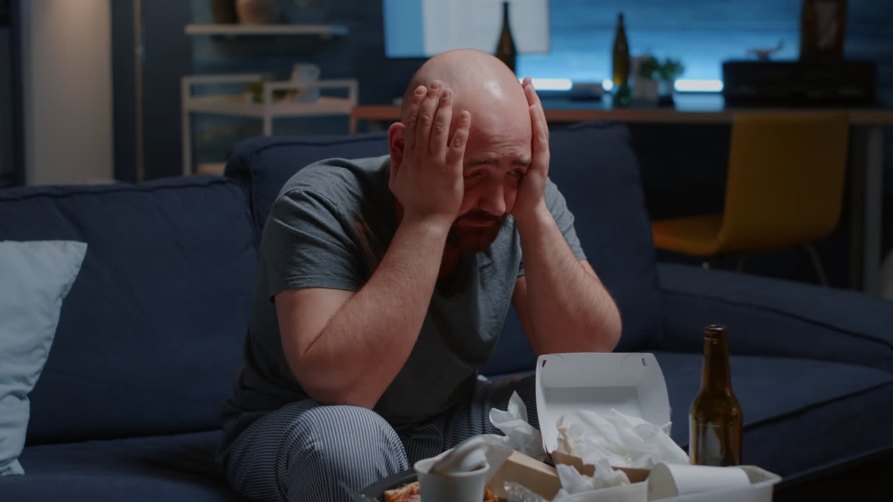 Triste uomo depresso seduto sul divano disperatamente affatica la solitudine